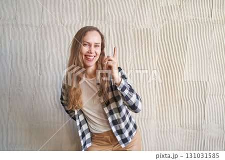 Smiling young caucasian female in checkered shirt pointing upwards against Smiling young caucasian female in checkered shirt pointing upwards against 131031585
