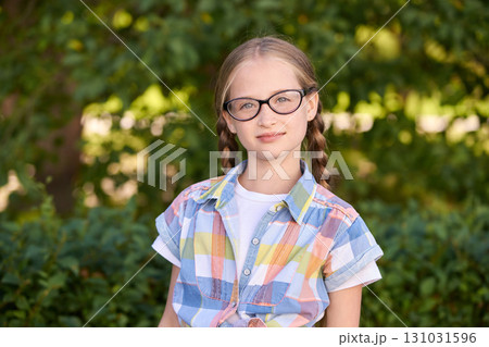 Caucasian young girl with glasses and braided hair in outdoor park setting 131031596