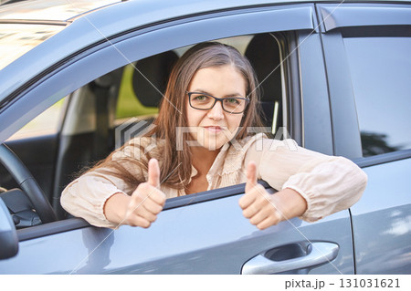 Caucasian female young adult giving thumbs up while sitting in a car, glasses Caucasian female young adult giving thumbs up while sitting in a car, glasses 131031621