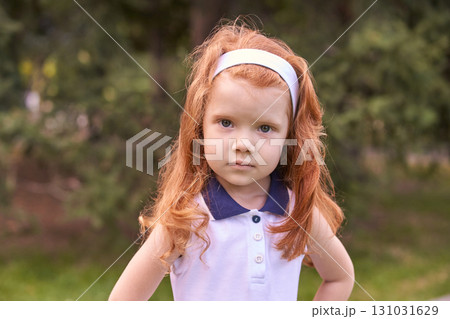 Serious young caucasian female child with red hair outdoors in a forested area 131031629