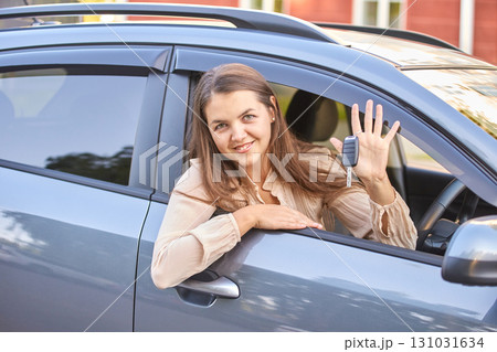 Young caucasian female smiling in car holding keys demonstrating new vehicle Young caucasian female smiling in car holding keys demonstrating new vehicle 131031634
