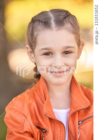 Smiling caucasian young girl in orange jacket outdoors with braided hair 131031652