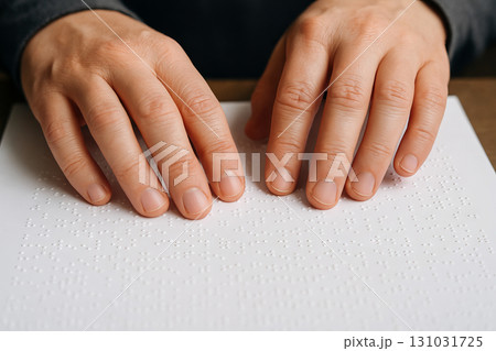 Hands gently reading braille text by touch, close-up of tactile learning experience and accessibility concept for individuals with visual impairments 131031725