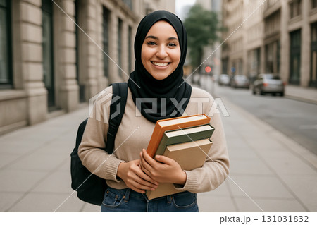 Smiling student in hijab holding books and backpack on city street for education and learning concept Smiling student in hijab holding books and backpack on city street for education and learning concept 131031832
