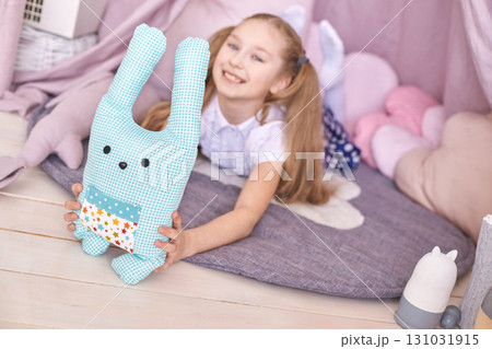 Caucasian young girl playing indoors with blue plush toy in cozy tent Caucasian young girl playing indoors with blue plush toy in cozy tent 131031915
