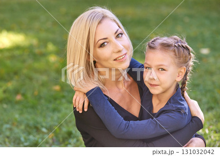 Caucasian adult female and young female child embracing outdoors in a park Caucasian adult female and young female child embracing outdoors in a park 131032042