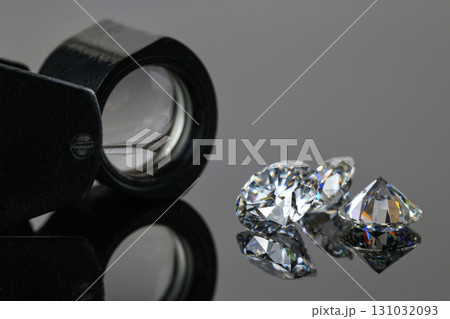 A magnifying glass is used to look at three diamonds 131032093