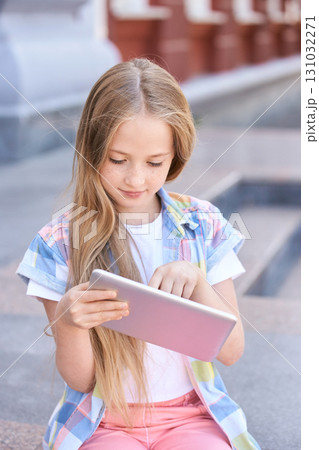 Young caucasian female child engaged with tablet in outdoor urban setting Young caucasian female child engaged with tablet in outdoor urban setting 131032271