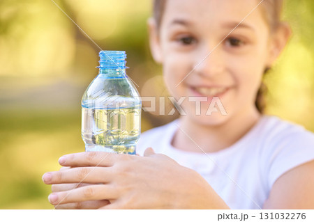 Caucasian young girl holding water bottle outdoors with joyful expression 131032276