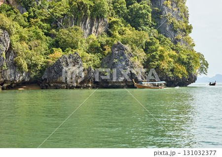 Scenic view of lush island landscape and traditional longtail boats on calm 131032377