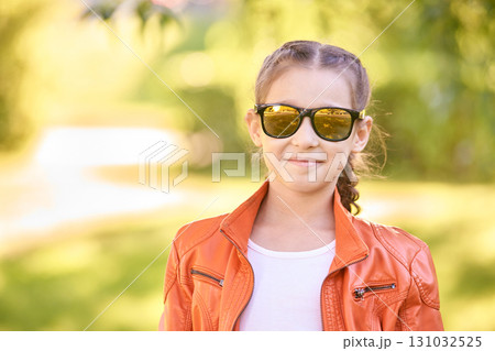 Young caucasian girl in orange jacket and sunglasses smiling outdoors Young caucasian girl in orange jacket and sunglasses smiling outdoors 131032525
