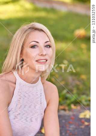Smiling caucasian female adult relaxing outdoors in sunlit park with autumn Smiling caucasian female adult relaxing outdoors in sunlit park with autumn 131032559