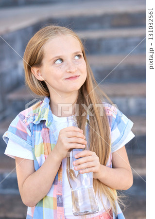 Caucasian young girl with long hair holding a glass bottle, wearing a colorful Caucasian young girl with long hair holding a glass bottle, wearing a colorful 131032561