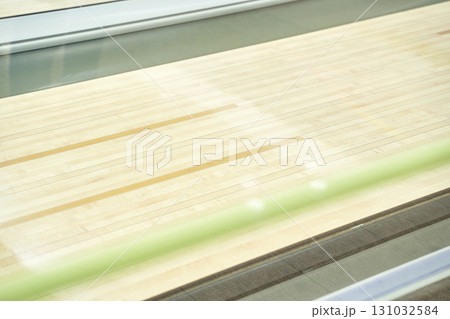 Empty bowling alley lane with polished wood surface and reflective lighting 131032584
