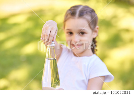 Caucasian female child holding glass bottle outdoors on a sunny day Caucasian female child holding glass bottle outdoors on a sunny day 131032831