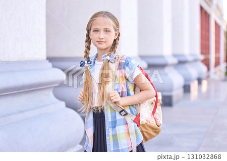 Caucasian female child with braids and backpack standing outdoors at school 131032868