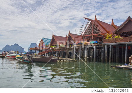 Traditional thai stilt houses over crystal blue water with boats 131032941