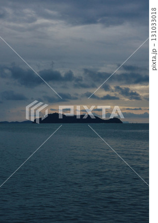 Serene evening seascape with distant island under cloudy sky reflecting in calm Serene evening seascape with distant island under cloudy sky reflecting in calm 131033018