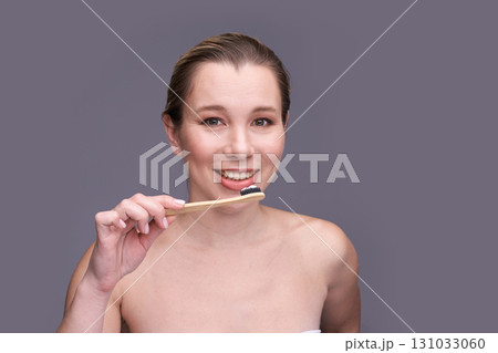 Caucasian young female brushing teeth with bamboo toothbrush smiling healthy 131033060