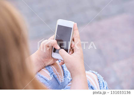 Young caucasian female using smartphone outdoors in casual ripped jeans Young caucasian female using smartphone outdoors in casual ripped jeans 131033136