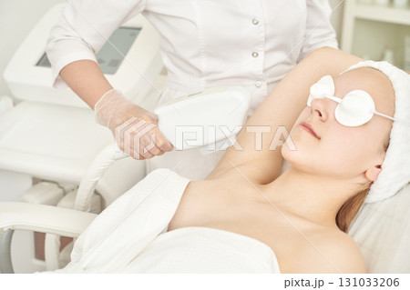 Caucasian female undergoing laser hair removal on underarm in professional spa Caucasian female undergoing laser hair removal on underarm in professional spa 131033206