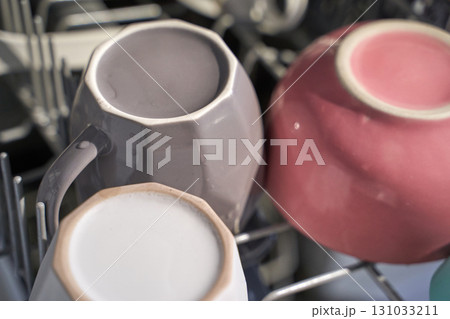 Three assorted ceramic coffee mugs in dishwasher rack with morning light Three assorted ceramic coffee mugs in dishwasher rack with morning light 131033211