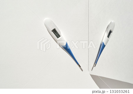 Two digital thermometers on white surface displaying temperature measurement 131033261