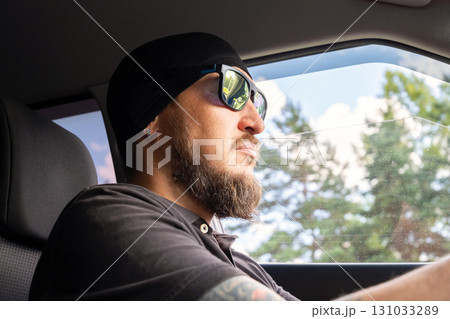 Man with beard and sunglasses driving car on sunny day. Man with beard and sunglasses driving car on sunny day. 131033289