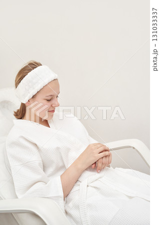 Young caucasian female relaxing in spa with white bathrobe and headband 131033337