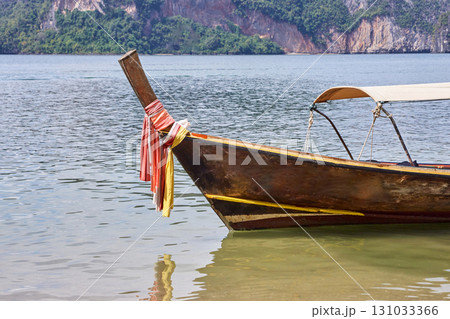Traditional thai longtail boat on tranquil sea with colorful fabrics tied 131033366