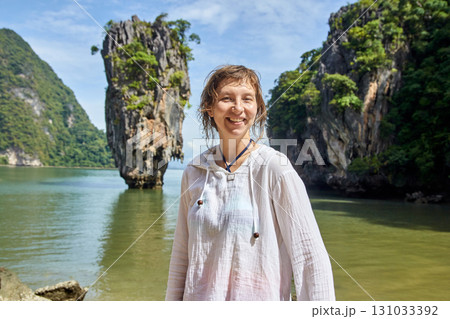 Female traveler smiling in front of limestone islands in sunny tropical waters Female traveler smiling in front of limestone islands in sunny tropical waters 131033392
