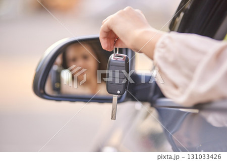 Woman reflects in car mirror holding keys in hand, ready for new journey Woman reflects in car mirror holding keys in hand, ready for new journey 131033426