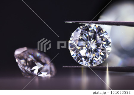 A diamond is being held up by a jeweler's loupe 131033552