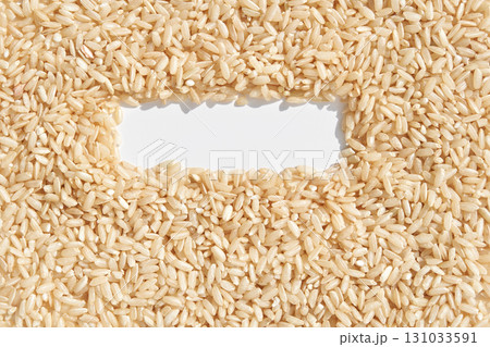 Brown rice grains forming a rectangular frame on white background 131033591