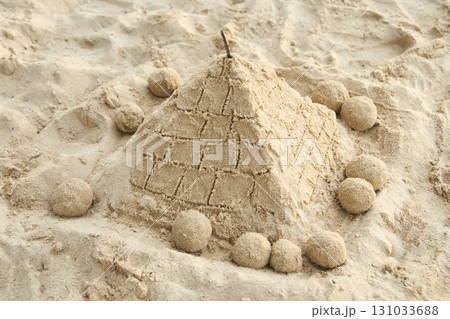 Sand pyramid on beach surrounded by spherical sand sculptures in sunlit setting 131033688