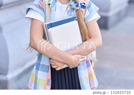 Young caucasian girl holding notebooks wearing colorful shirt and backpack Young caucasian girl holding notebooks wearing colorful shirt and backpack 131033710