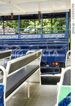 Empty open-air safari tour bus with blue interior in tropical jungle setting Empty open-air safari tour bus with blue interior in tropical jungle setting 131033769