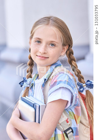 Caucasian young female student with braided hair holding books and smiling Caucasian young female student with braided hair holding books and smiling 131033795