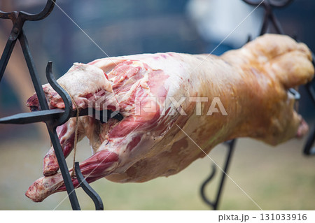 mutton carcass on a spit is roasted whole in close-up mutton carcass on a spit is roasted whole in close-up 131033916