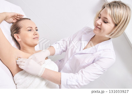 Young caucasian female undergoing professional armpit waxing treatment Young caucasian female undergoing professional armpit waxing treatment 131033927