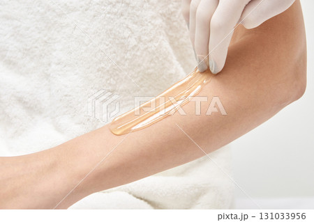 Close-up of female arm undergoing smooth waxing treatment with gloved hand Close-up of female arm undergoing smooth waxing treatment with gloved hand 131033956