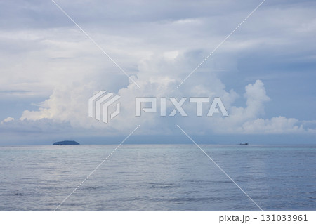 Vast ocean view with distant island and boat under expansive cloudy sky Vast ocean view with distant island and boat under expansive cloudy sky 131033961