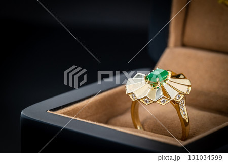 A gold and green ring is in a box 131034599