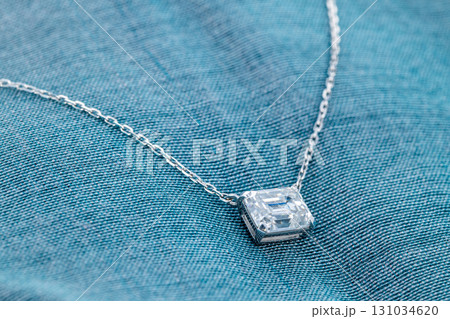 A necklace with a diamond pendant is on a blue cloth 131034620