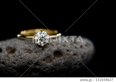 A gold and diamond ring is sitting on a rock 131034627