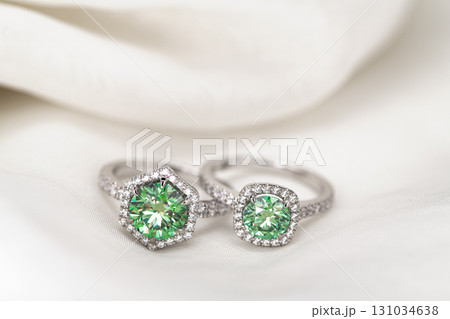 Two green gemstone rings are displayed on a white cloth Two green gemstone rings are displayed on a white cloth 131034638