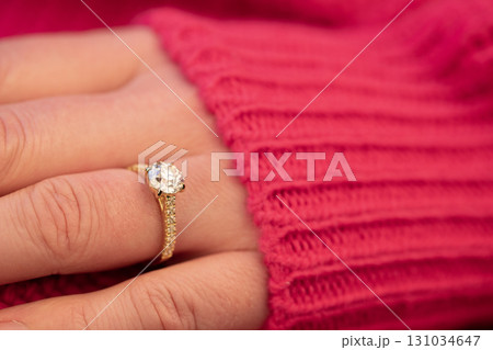 A gold ring with a diamond on it is shown on a person's finger A gold ring with a diamond on it is shown on a person's finger 131034647