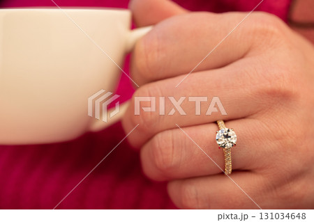 A woman is holding a cup and a ring 131034648