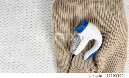 A lint remover against a warm cozy sweater with bobbles. Preparing wardrobe and caring for clothes, clothing care and maintenance, fall and winter fashion and garment preparation A lint remover against a warm cozy sweater with bobbles. Preparing wardrobe and caring for clothes, clothing care and maintenance, fall and winter fashion and garment preparation 131035994
