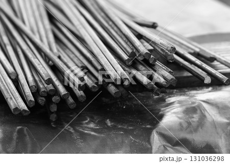 Steel reinforcement bars are piled outdoor. Black and white photo Steel reinforcement bars are piled outdoor. Black and white photo 131036298